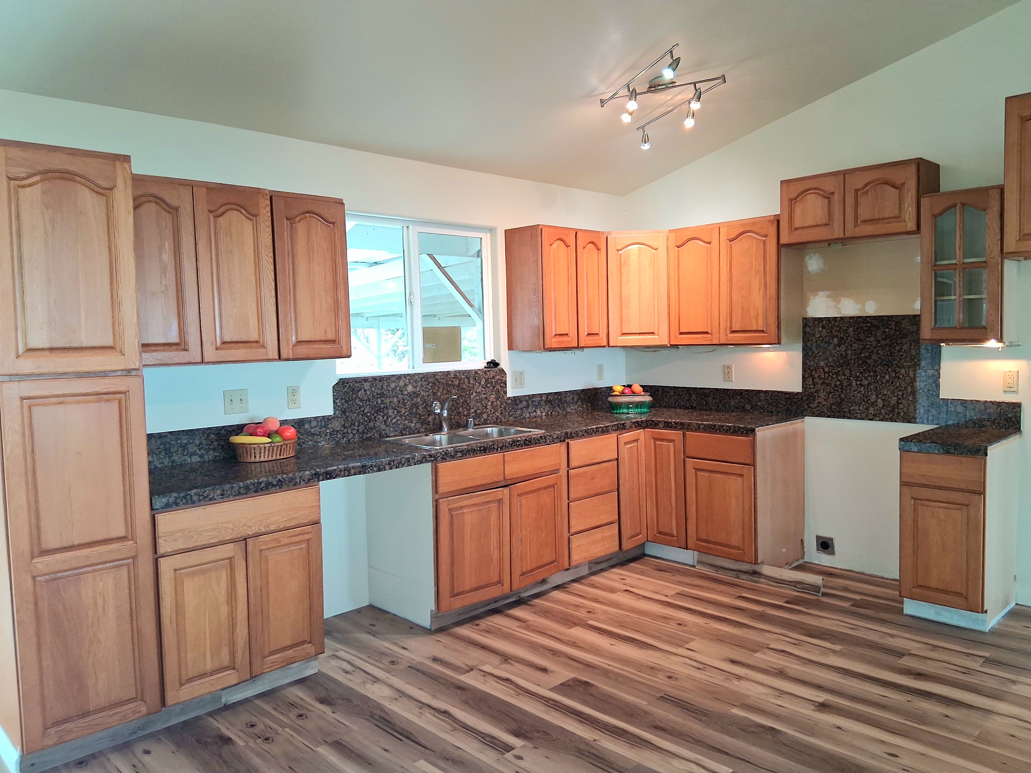 92-8221 Reef Parkway Ocean View, HI 96704 - Photo 7 of 20 a kitchen with granite countertop a stove a sink dishwasher and cabinets with wooden floor