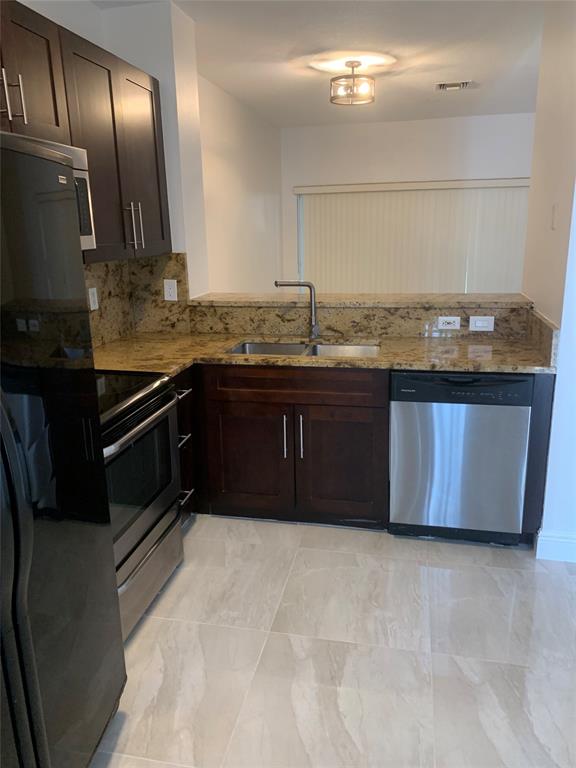 12017 Southwest 2nd Street, Unit 12017 Pembroke Pines, FL 33025 - Photo 1 of 13 a kitchen with granite countertop stainless steel appliances and wooden cabinets