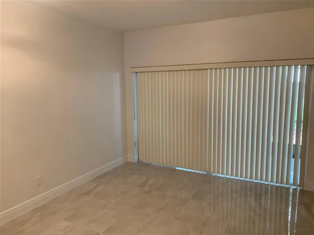 en empty room with chandelier fan and kitchen view