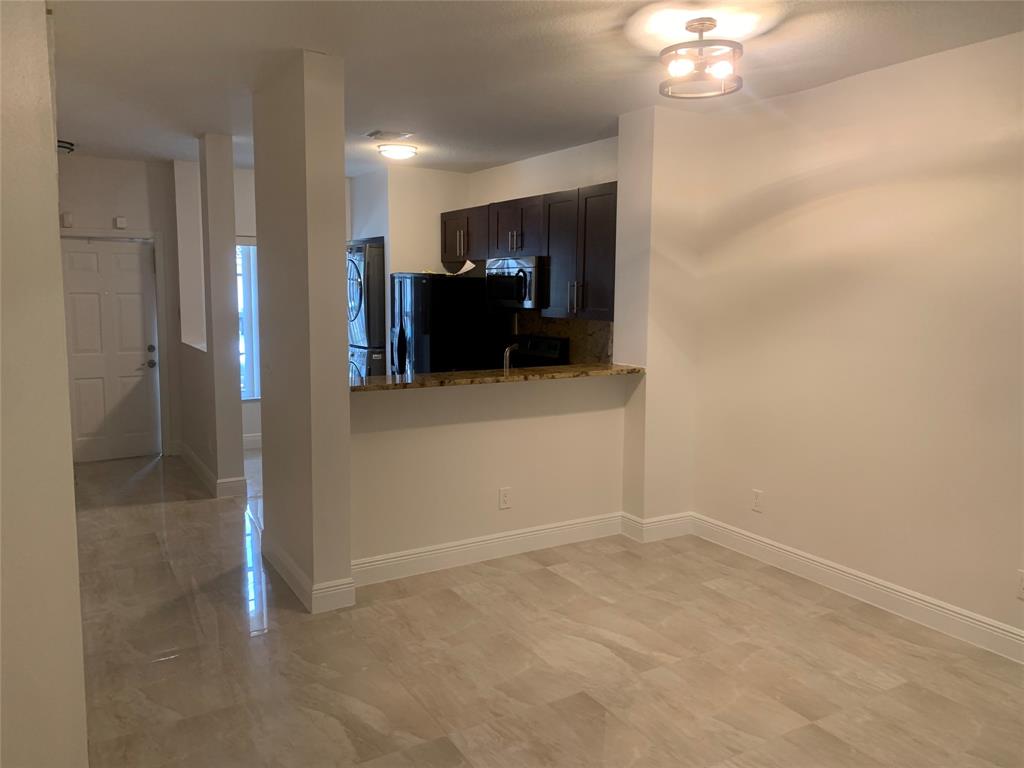 12017 Southwest 2nd Street, Unit 12017 Pembroke Pines, FL 33025 - Photo 7 of 13 en empty room with chandelier fan and kitchen view