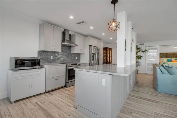 a kitchen with stainless steel appliances kitchen island granite countertop a stove a sink and a wooden floors