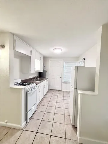 a kitchen with granite countertop a refrigerator and a stove top oven