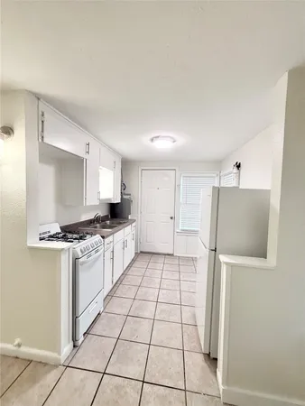 a kitchen with granite countertop a refrigerator and a stove top oven