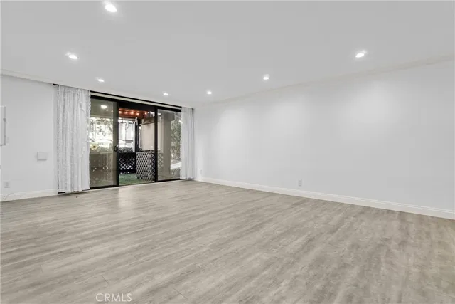 a view of an empty room with window and wooden floor