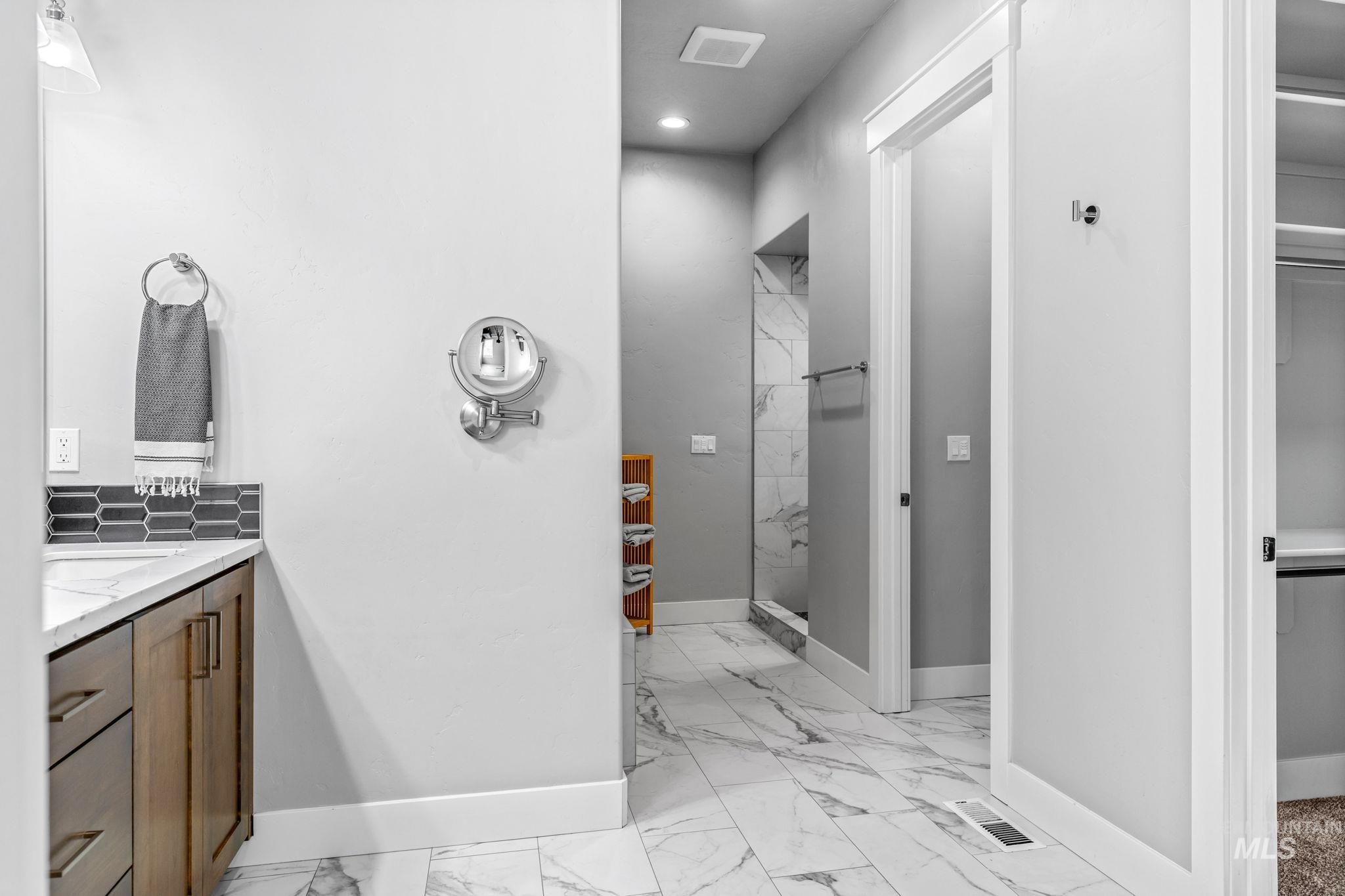 2934 East Murchison Street Meridian, ID 83642 - Photo 23 of 44 Bathroom featuring wood-finish cabinetry, a white countertop, and gray picket tile backsplash