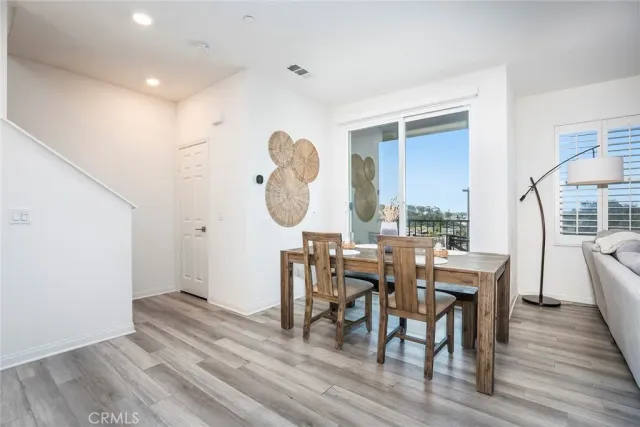 a view of a dining room and livingroom with furniture wooden floor a rug and a large window