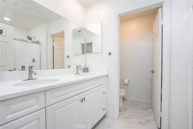 a bathroom with a granite countertop sink a toilet and a mirror