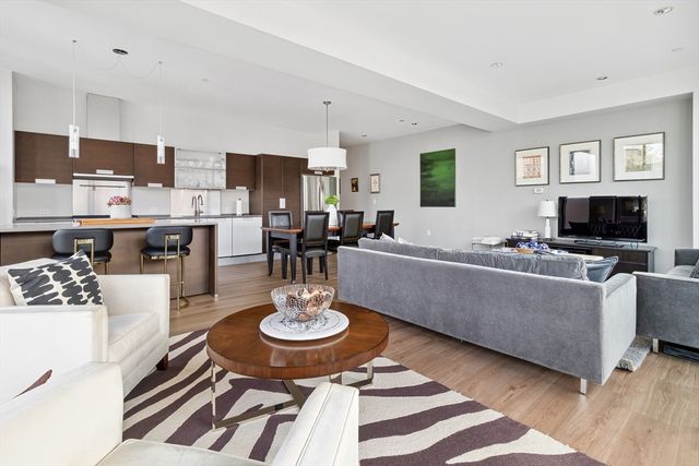 a living room with couches a coffee table and kitchen view with wooden floor