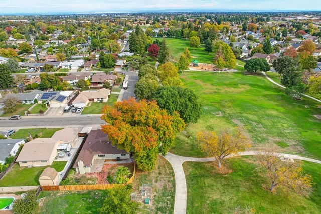 an aerial view of residential houses with outdoor space and trees
