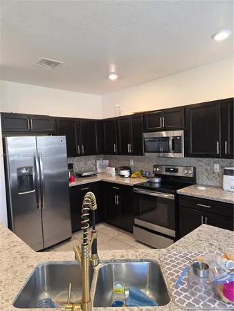 a kitchen with stainless steel appliances kitchen island granite countertop a refrigerator and a stove top oven