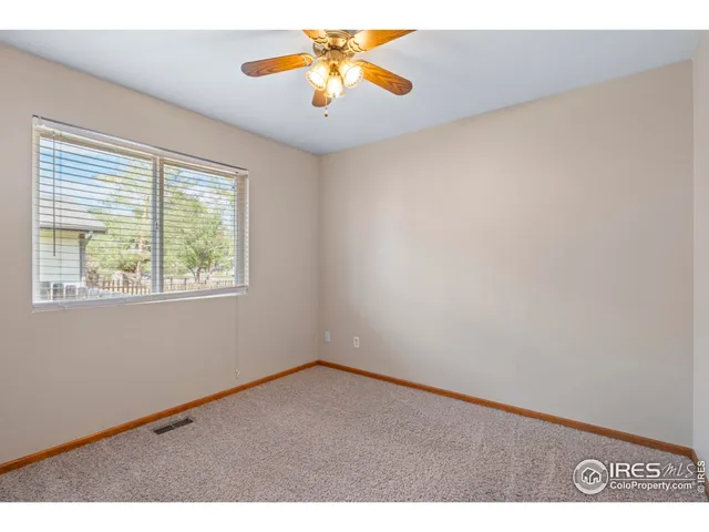 an empty room with windows and chandelier fan