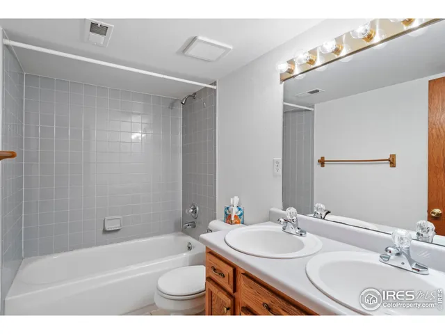 a bathroom with a granite countertop sink a toilet a mirror a bathtub and shower