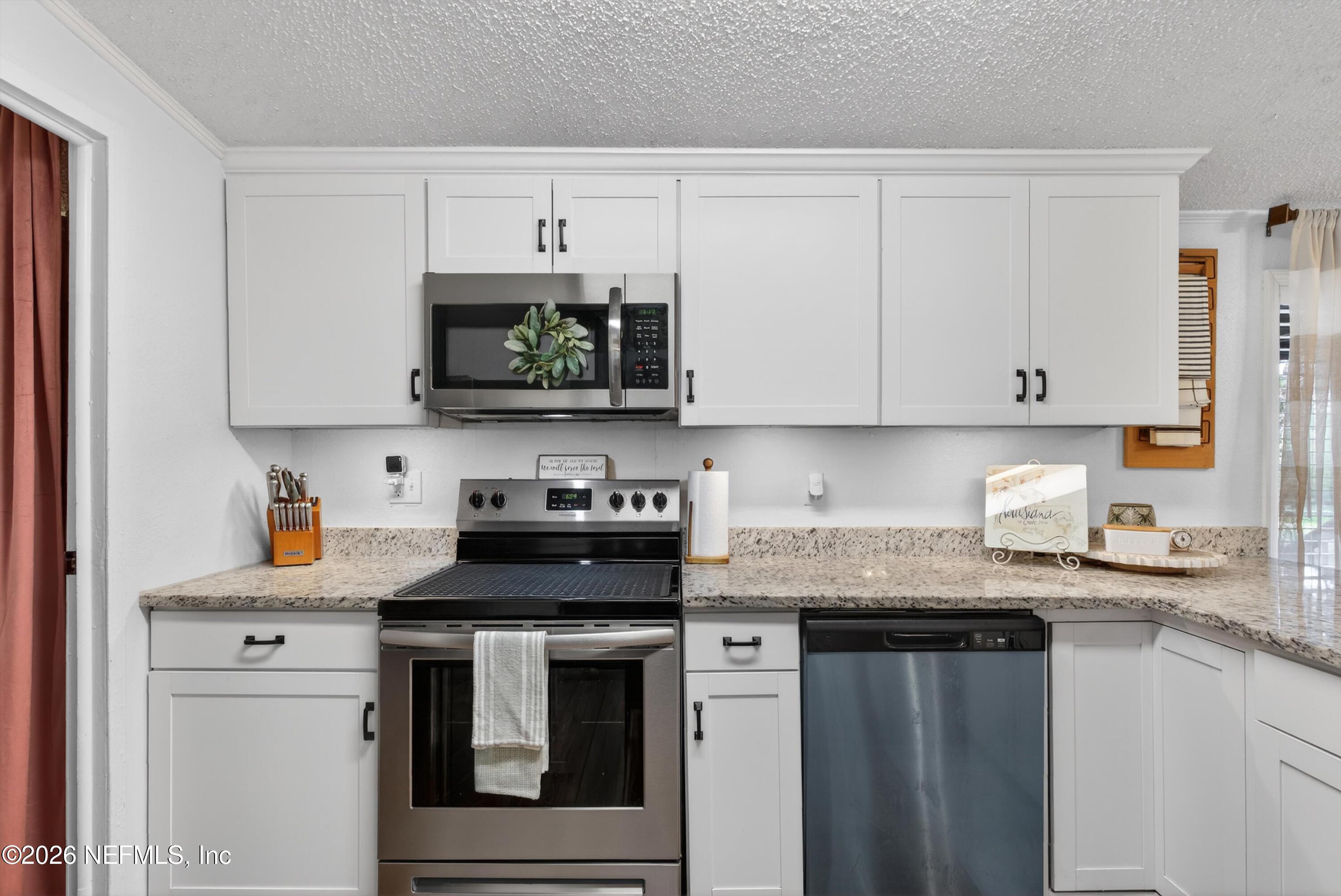 7655 Long Lake Road Keystone Heights, FL 32656 - Photo 16 of 58 a kitchen with granite countertop white cabinets and a stove with wooden floor