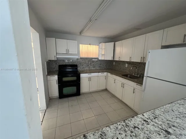 a kitchen with granite countertop white cabinets and white appliances