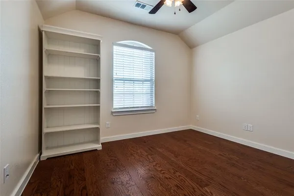 a view of an empty room with a window and wooden floor