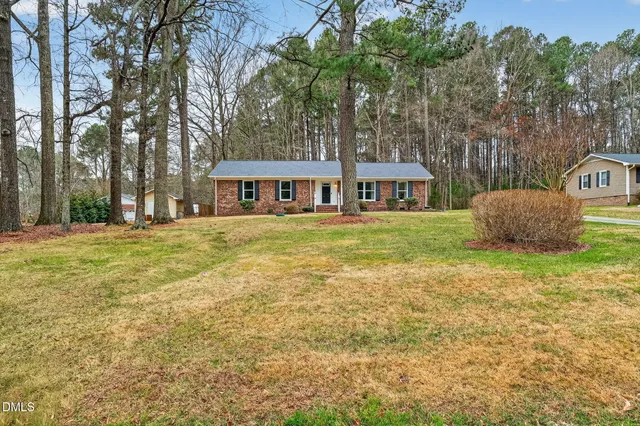 a front view of a house with a garden and tree