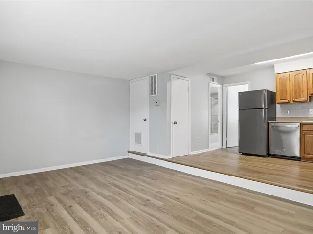 a view of a kitchen with refrigerator and wooden floor