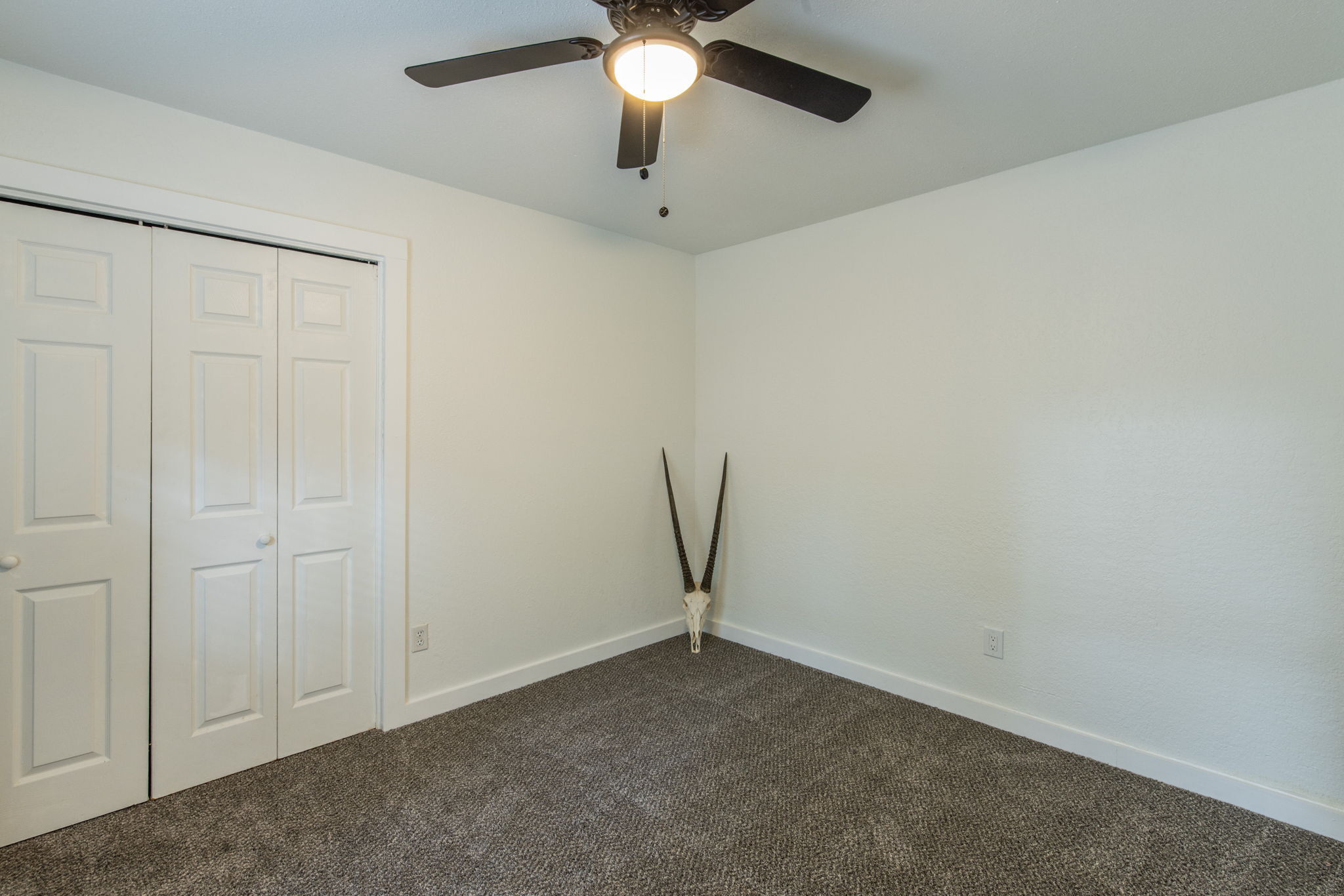 1008 Milford Way Austin, TX 78745 - Photo 35 of 40 Bedroom featuring light neutral walls, textured carpeting, white baseboards, a ceiling fan with integrated lighting, and bi-fold closet doors