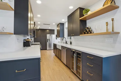 a kitchen with a sink stainless steel appliances wooden floor and cabinets