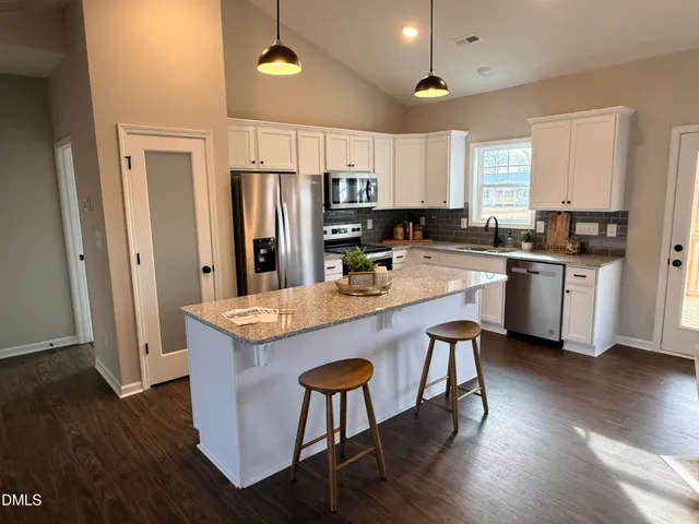 a kitchen with stainless steel appliances a stove a sink a refrigerator and wooden floor