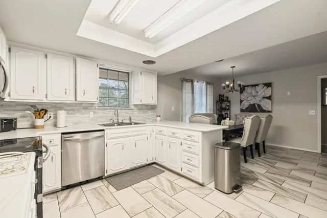 a kitchen with granite countertop white cabinets stainless steel appliances and a sink