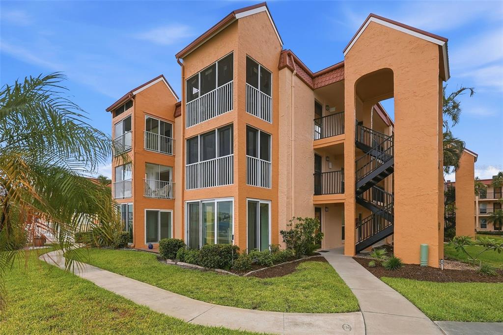 8921 Blind Pass Road, Unit 144 St. Pete Beach, FL 33706 - Photo 27 of 37 a front view of a multi story residential apartment building with yard and green space