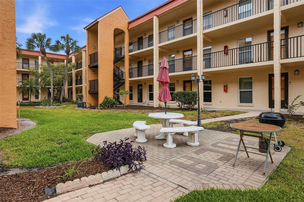 8921 Blind Pass Road, Unit 144 St. Pete Beach, FL 33706 - Photo 30 of 37 a view of a building with a garden and sitting area