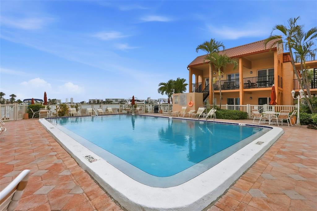 8921 Blind Pass Road, Unit 144 St. Pete Beach, FL 33706 - Photo 37 of 37 a view of a swimming pool with a lounge chairs