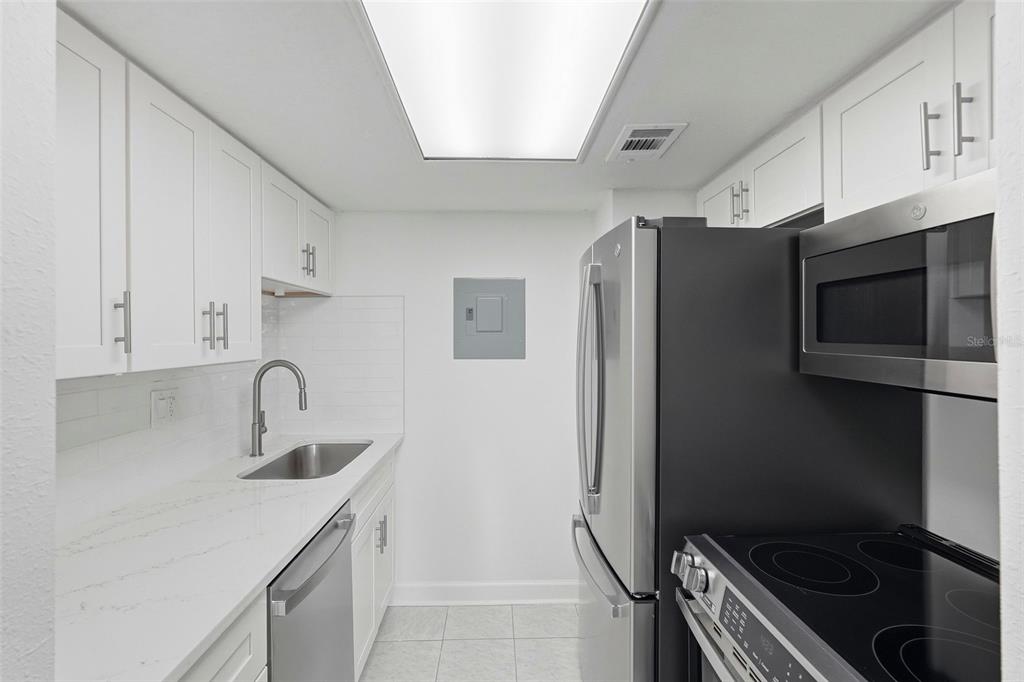 8921 Blind Pass Road, Unit 144 St. Pete Beach, FL 33706 - Photo 4 of 37 a kitchen with stainless steel appliances a refrigerator a sink a stove and cabinets
