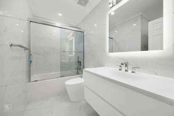 a bathroom with a bathtub shower sink mirror and toilet