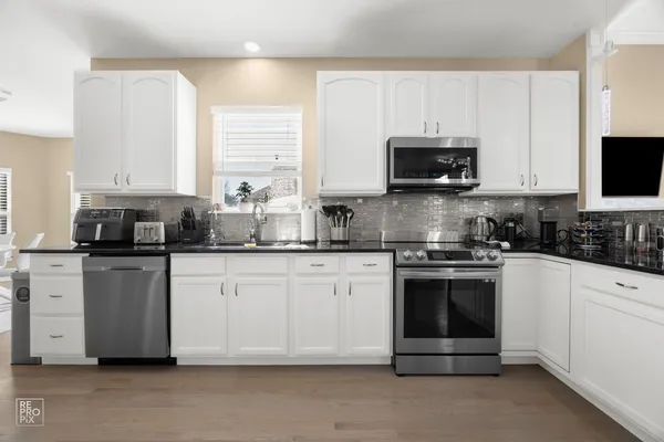 a kitchen with stainless steel appliances granite countertop a stove a sink and a microwave