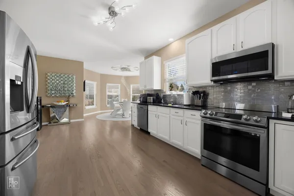 a kitchen with stainless steel appliances a stove a sink dishwasher a microwave oven and a stove with wooden floor