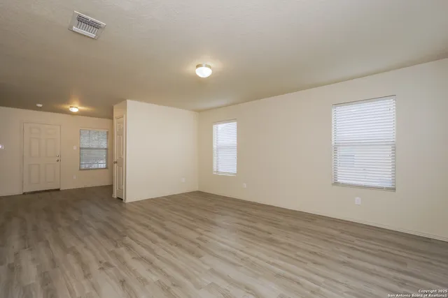an empty room with wooden floor and windows