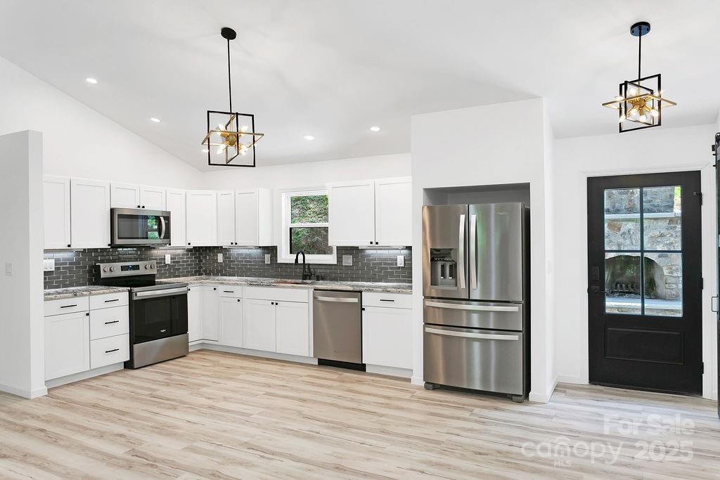 147 Wood Road Brevard, NC 28712 - Photo 8 of 24 a kitchen with stainless steel appliances granite countertop a refrigerator a stove a sink dishwasher a oven a dining table and chairs with wooden floor