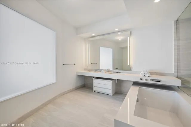a large white bathroom with a double vanity sink a toilet a mirror and shower