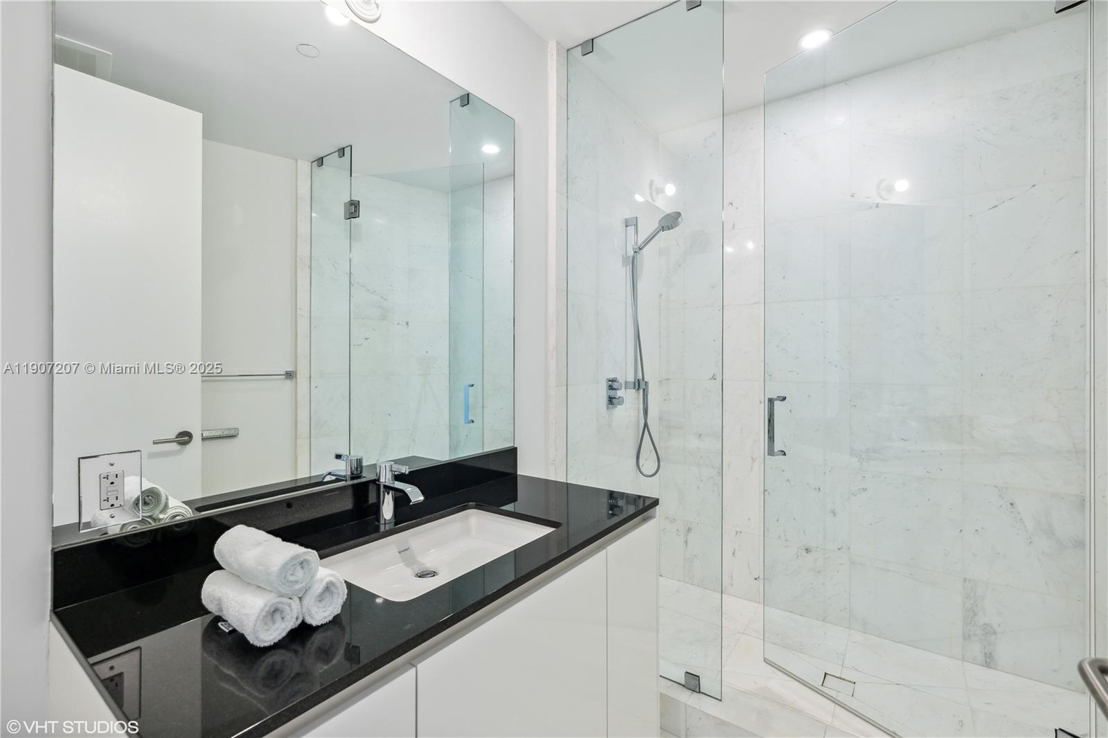 18555 Collins Avenue, Unit 1101 Sunny Isles Beach, FL 33160 - Photo 40 of 46 a bathroom with a granite countertop sink a shower and a mirror