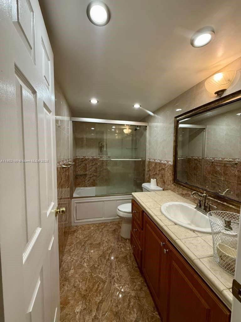 5401 Collins Avenue, Unit 131 Miami Beach, FL 33140 - Photo 11 of 33 a bathroom with a double vanity sink toilet mirror and bathtub