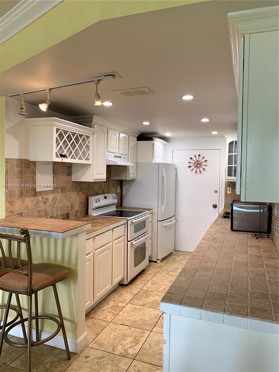 5401 Collins Avenue, Unit 131 Miami Beach, FL 33140 - Photo 4 of 33 a large kitchen with stainless steel appliances kitchen island granite countertop a sink and cabinets
