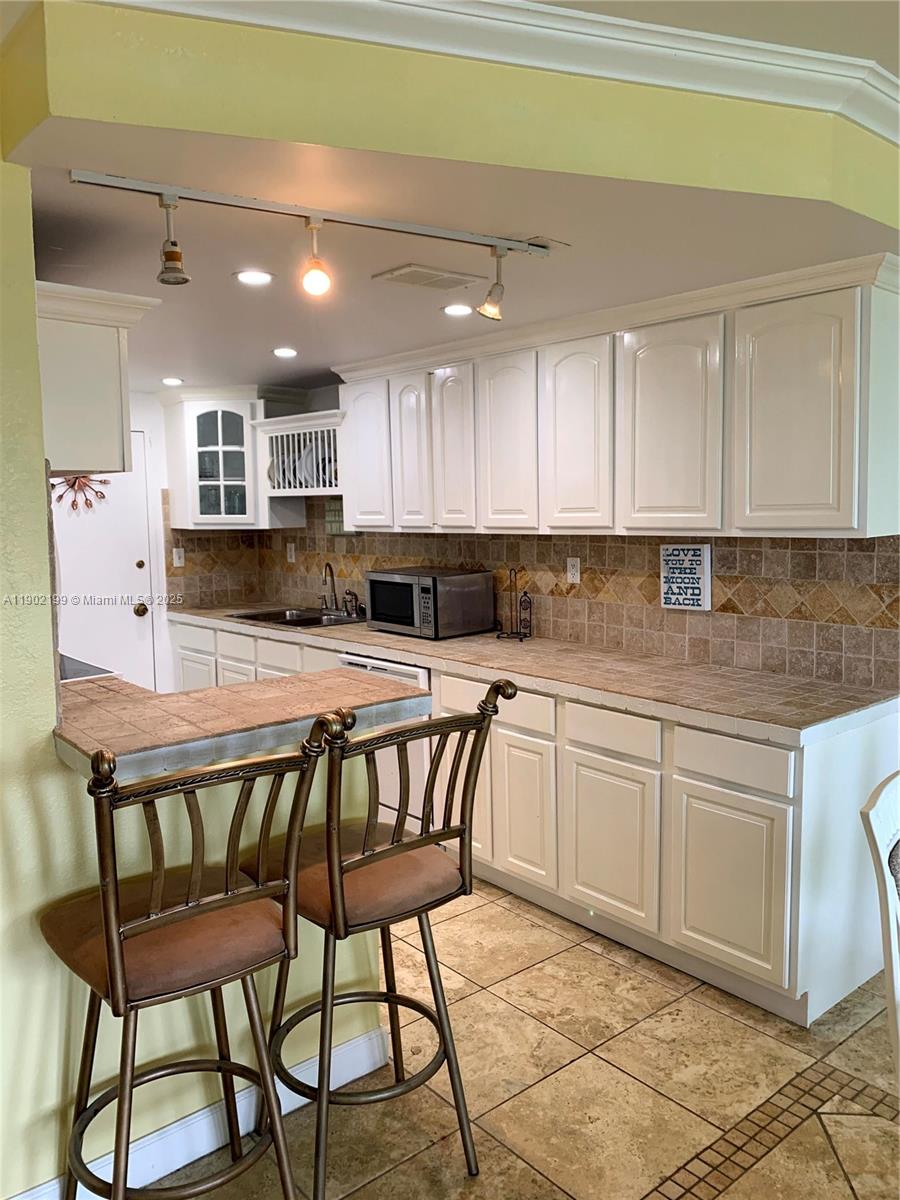5401 Collins Avenue, Unit 131 Miami Beach, FL 33140 - Photo 5 of 33 a kitchen with stainless steel appliances granite countertop a table chairs sink and cabinets