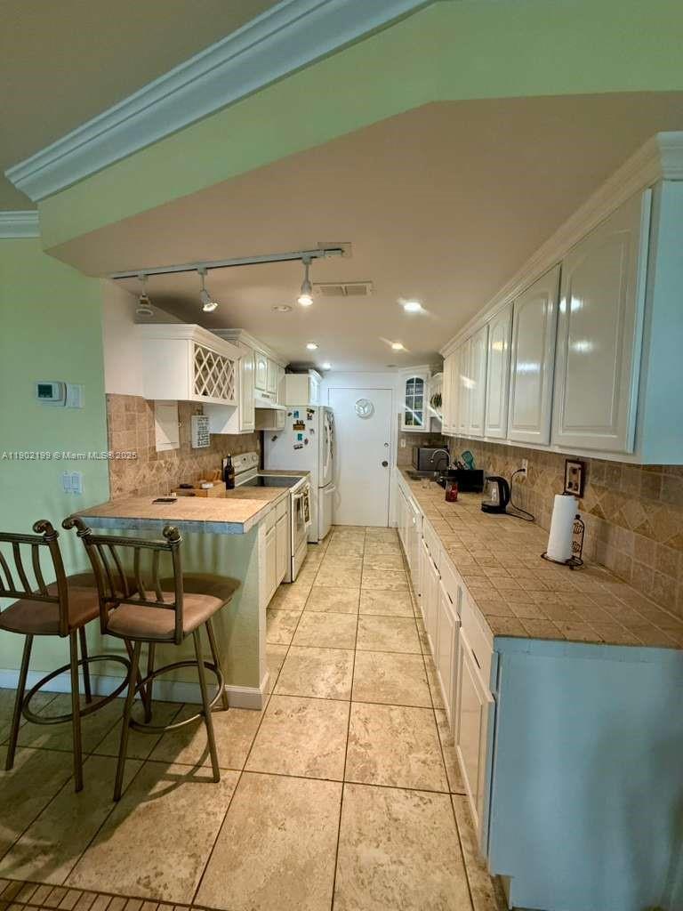 5401 Collins Avenue, Unit 131 Miami Beach, FL 33140 - Photo 6 of 33 a kitchen with stainless steel appliances kitchen island granite countertop a table chairs sink and cabinets