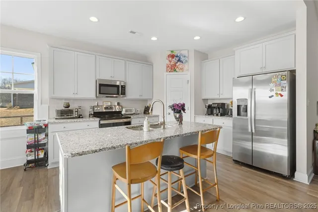 a kitchen with granite countertop a refrigerator stove microwave and cabinets