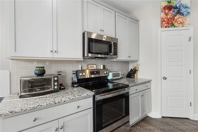 a kitchen with granite countertop white cabinets and black appliances