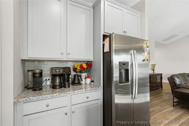 a kitchen with granite countertop a refrigerator and cabinets