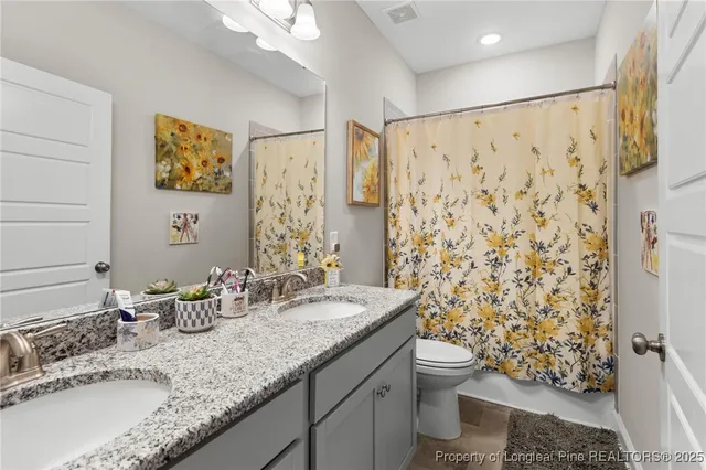 a bathroom with a granite countertop sink a toilet and a shower curtain