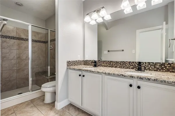 a bathroom with a granite countertop sink a toilet and shower