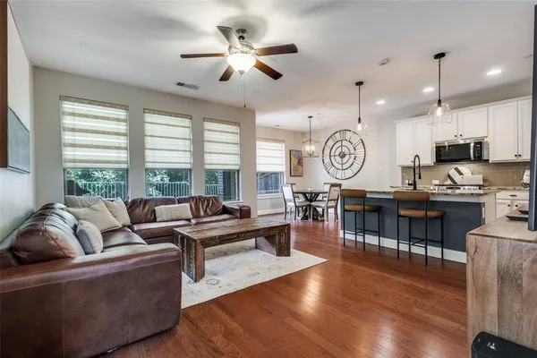 a living room with couch kitchen view and a large window