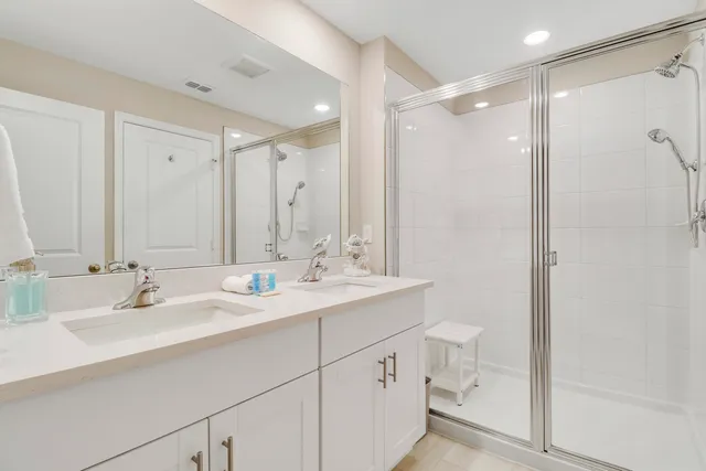 a bathroom with double vanity sink a mirror and a shower