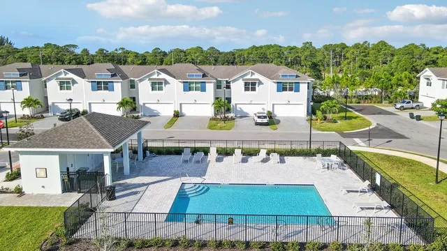 a view of a white house with a swimming pool and chairs