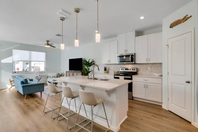 a kitchen with stainless steel appliances granite countertop a stove a sink a microwave a dining table and chairs with wooden floor