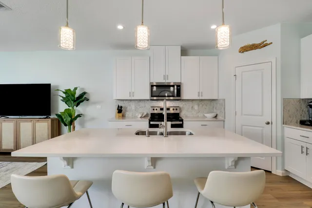 a kitchen with stainless steel appliances a white table chairs and a refrigerator